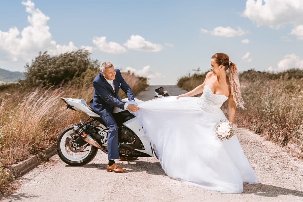 Ella a Miro na bielej motorke, ženích drží dlhú sukňu nevestiných šiat
