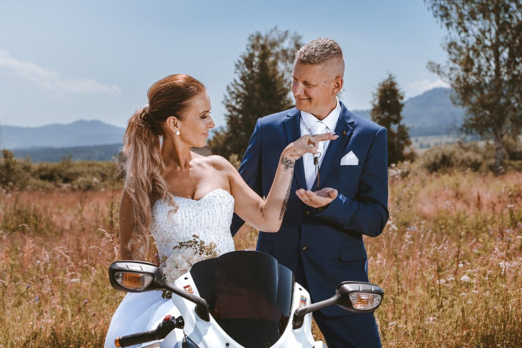 Ella a Miro pri bielej motorke, nevesta sa dotýka ženíchovho saka