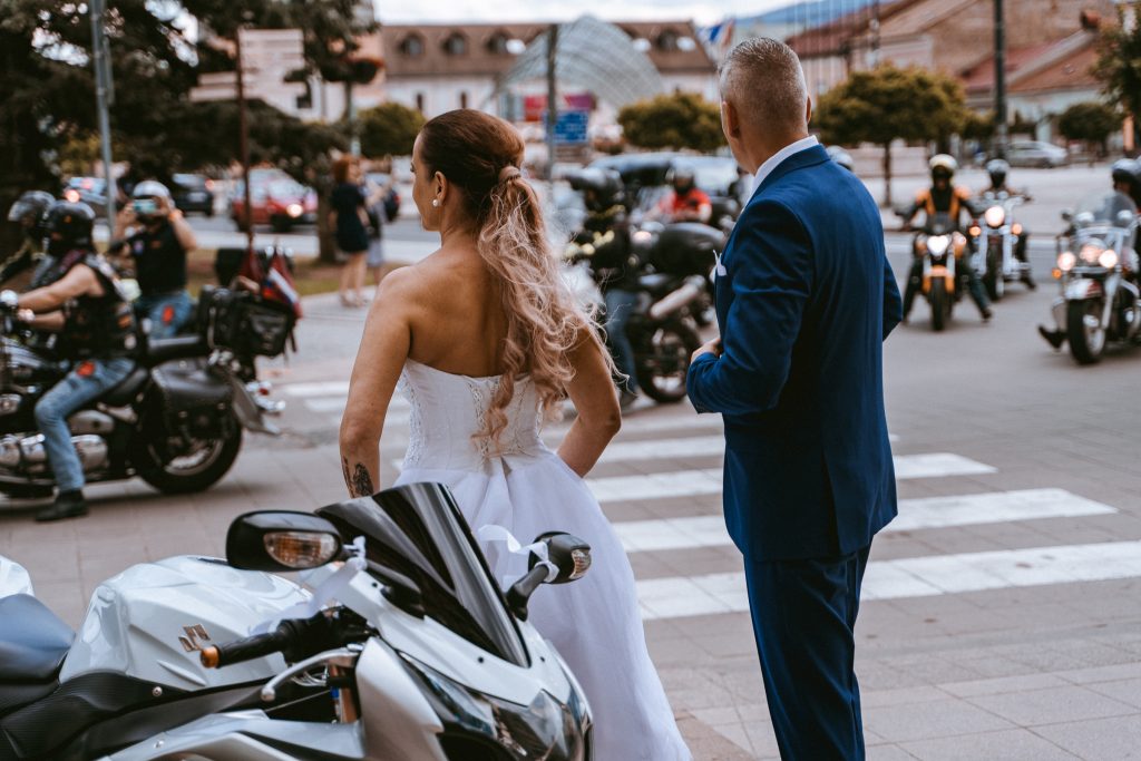 Nevesta a ženích pozerajú na kolónu motoriek na ulici mesta