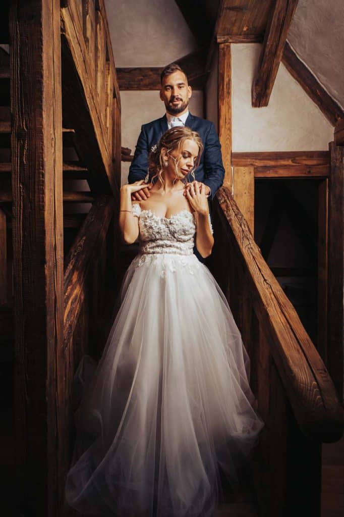 Dominika a Michal na drevenom schodisku, ženích ju objíma zozadu