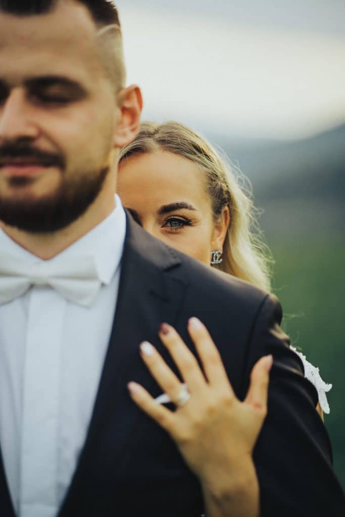 Nevesta položila ruku s prsteňom na ženíchovu hruď, v pozadí príroda