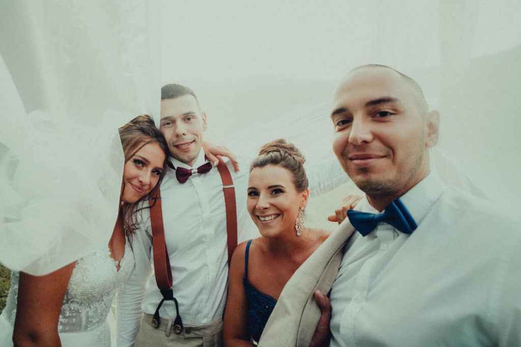 Nevesta s tromi hosťami pri spoločnej selfie pod svadobným závojom