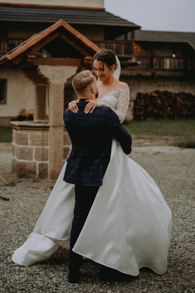 Anička a Tibor sa objímajú na štrkovom nádvorí pred drevenou stavbou