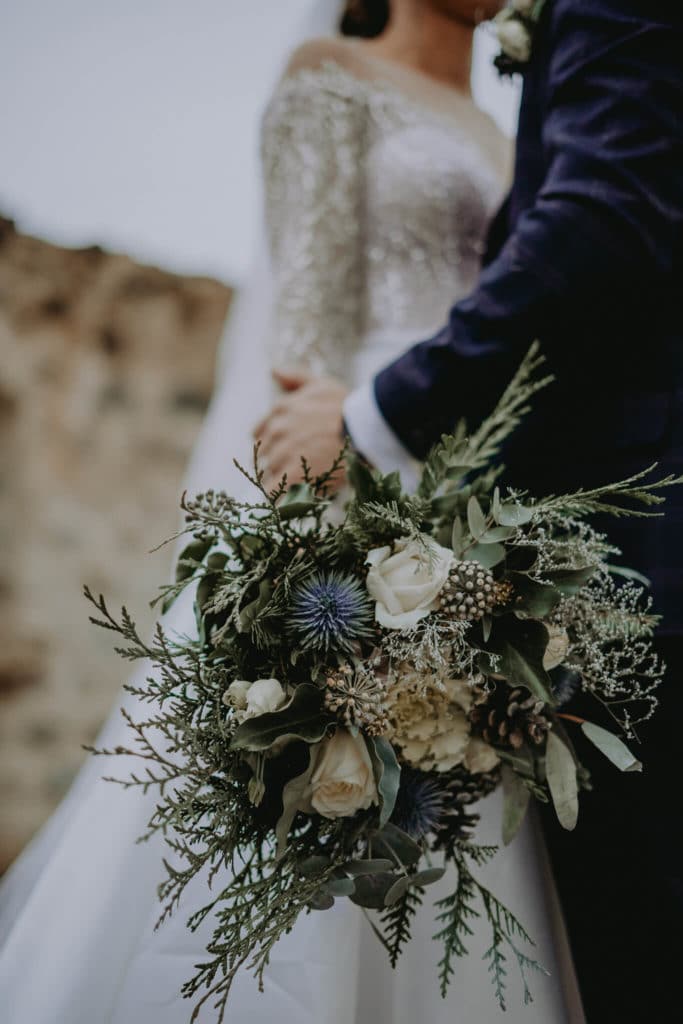 Detail nevestinej kytice so zeleňou, bielymi kvetmi a modrým bodliakom