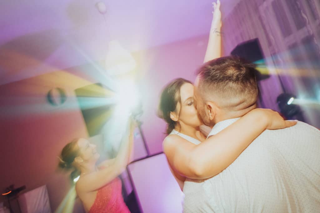 Novomanželia sa objímajú a tancujú vo farebných svetlách na zábave