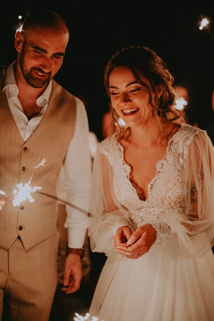 Smejúca sa nevesta a ženích držia v tme iskriace prskavky