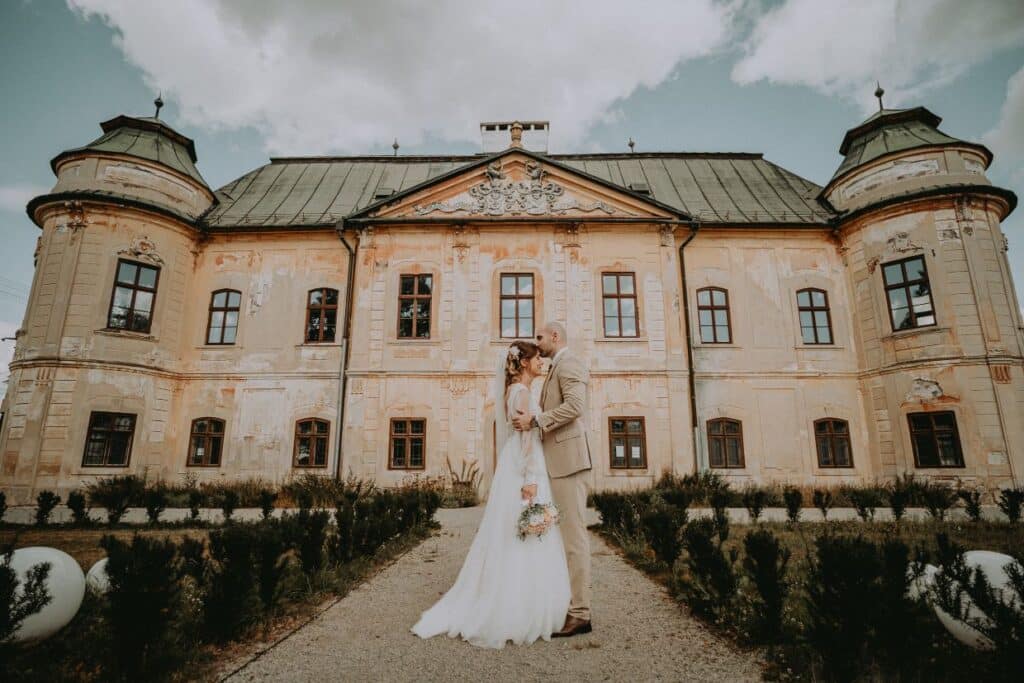 Mirka a Jano sa bozkávajú na chodníku pred kaštieľom v Hronseku s vežami