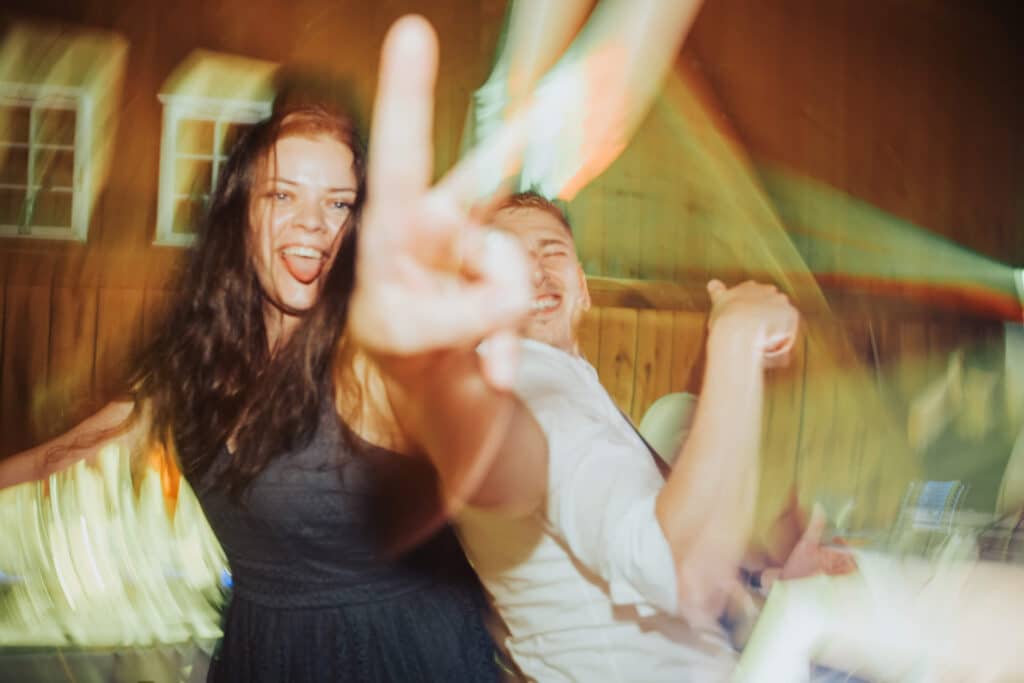 Smejúca sa hostka ukazuje znak V počas divokej tanečnej zábavy