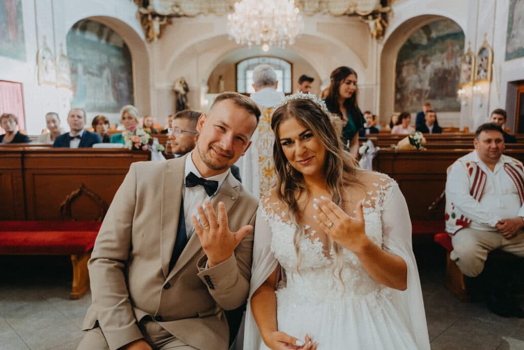 Katka a Michal sa usmievajú a ukazujú obrúčky počas obradu v kostole