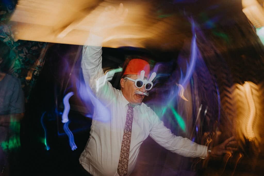 Hosť v červenom klobúku a kravate divoko tancuje medzi svetlami